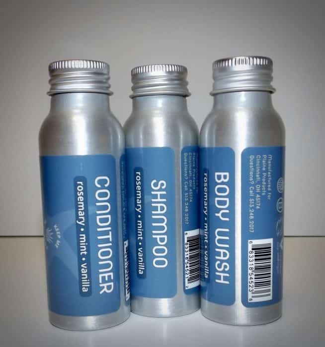 A set of travel size shampoo, conditioner, and body wash in metal containers.