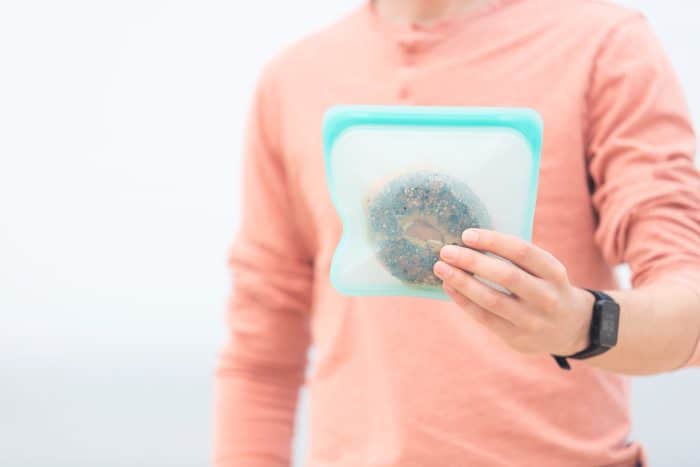 Man holding reusable silicone bag with a bagel in it